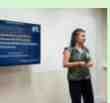 Pesquisadora apresentando estudo com slide azul em sala de aula